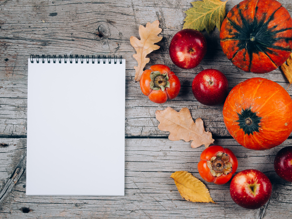 fall squash, vegetables and flowers beside a pad of paper